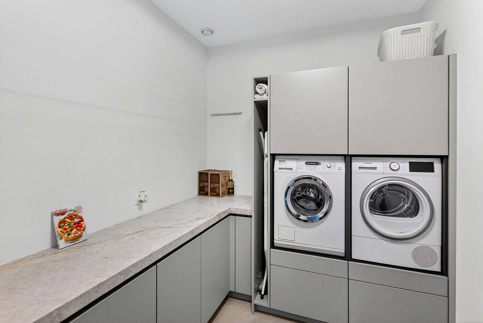 Bijkeuken inspiratie: grijze bijkeuken met verhoogde wasmachine- en droger en ruimte voor strijkplank