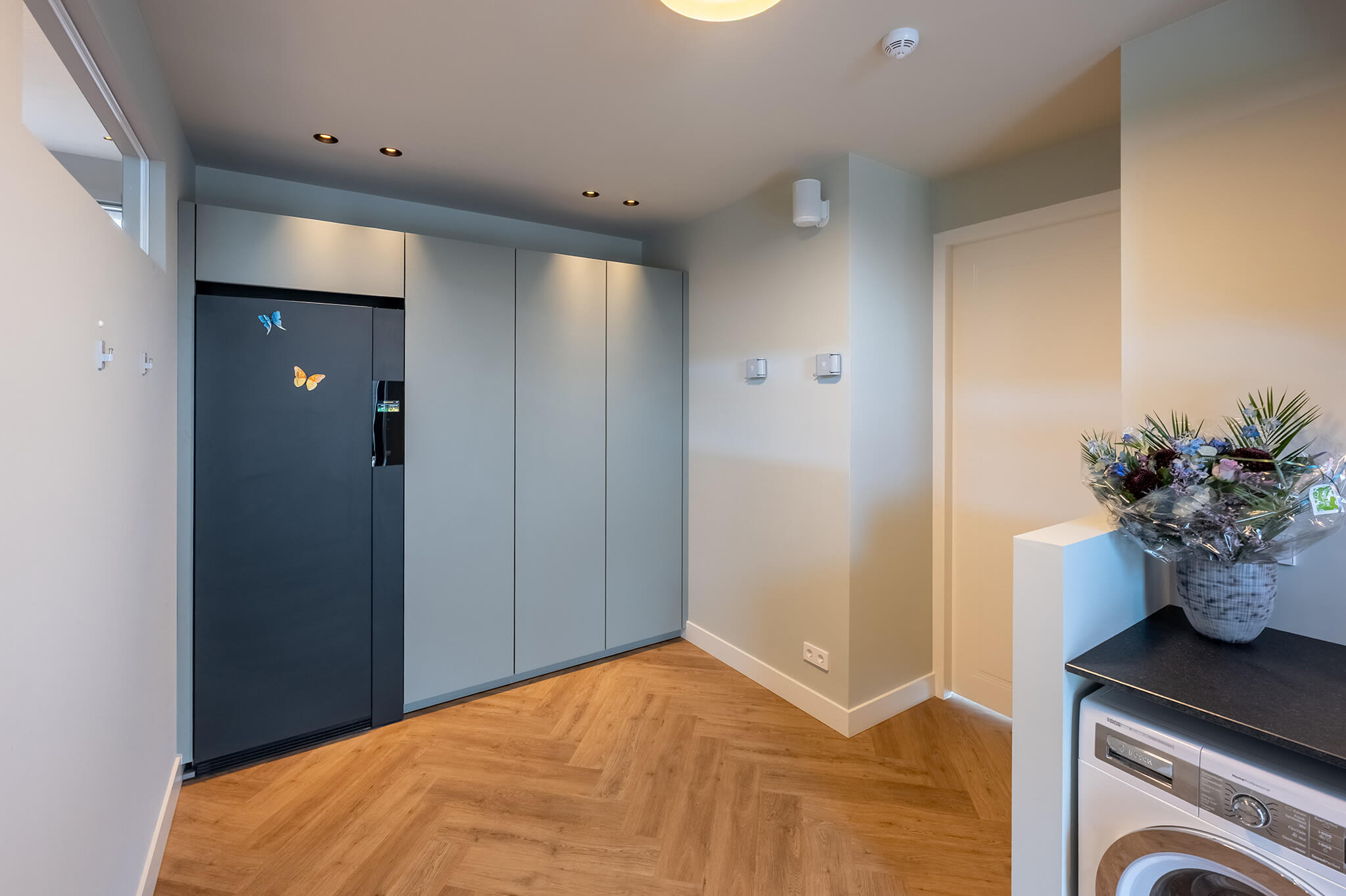 Praktisch ingerichte bijkeuken met grote kastenwand.